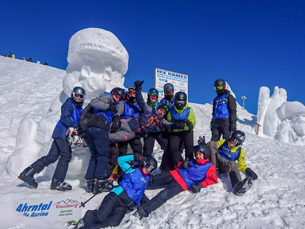 Jugendliche sitzen vor den Schneeskulpturen der Bergstation.